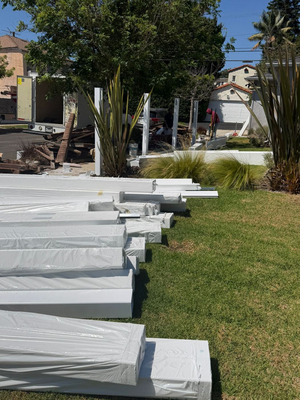 Vinyl fence panels and posts delivered to a job site while the old fence comes out