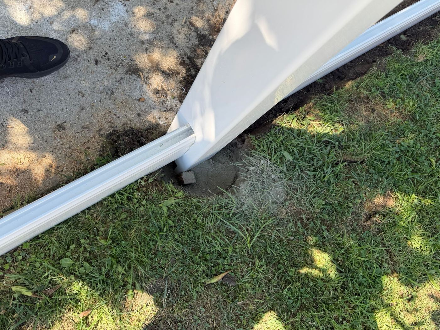 Vinyl fence post set in a concrete footing