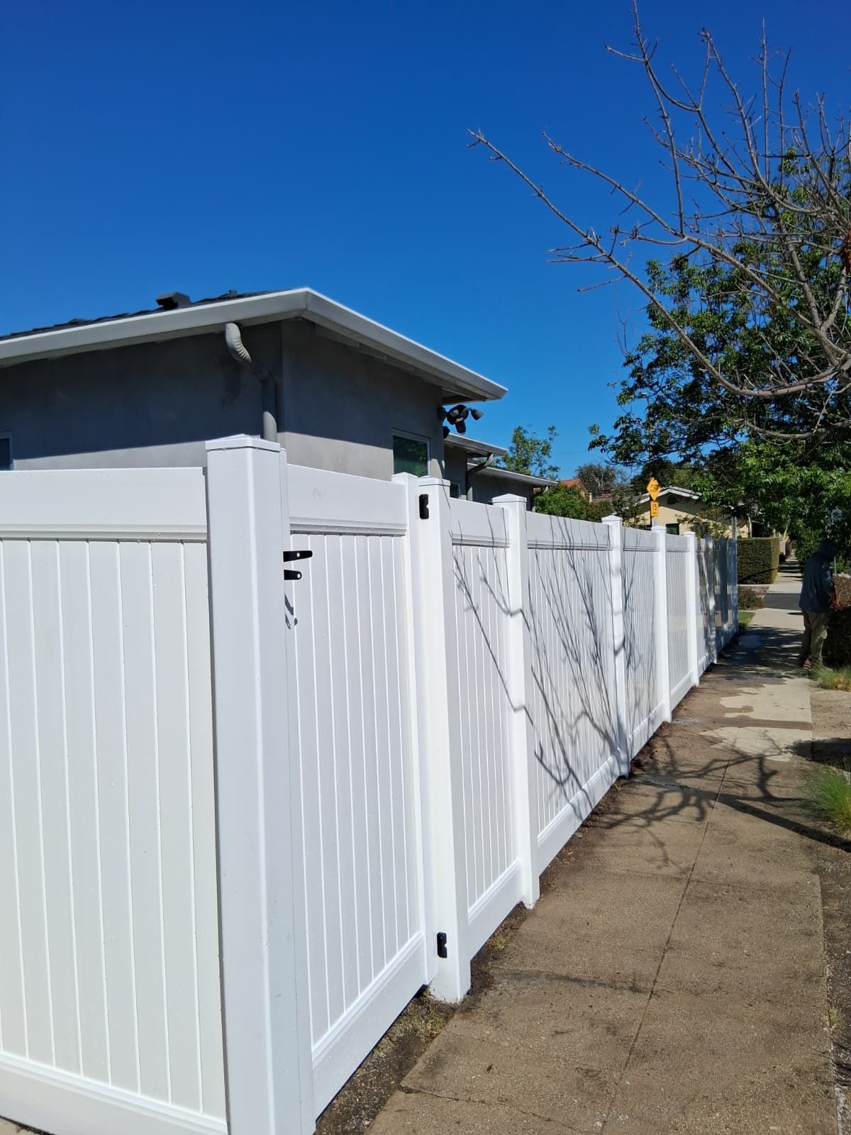 Finished white vinyl fence and gate along a sidewalk